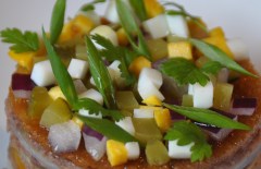 les petits dés de cornichons, d’oignons rouges et d’œuf dur avec un filet d’huile d’olive