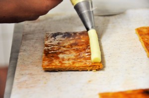 Avec une poche à dresser  répartir une couche régulière de crème mousseline en laissant un espace au centre pour ajouter les fraises.